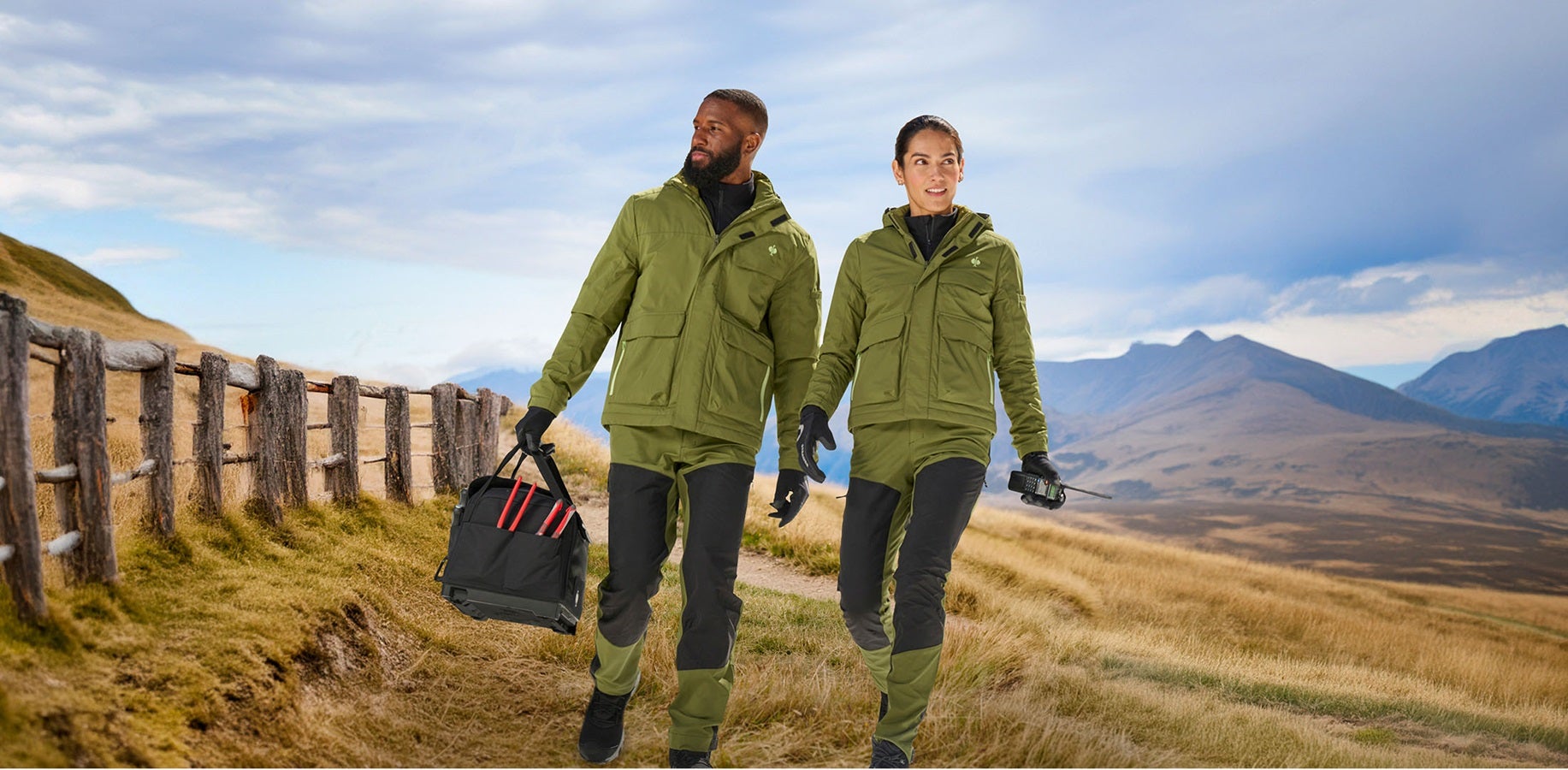 Un uomo e una donna indossano una giacca invernale e.s.trail e pantaloni funzionali ibridi e.s.trail in verde ginepro/verde lime